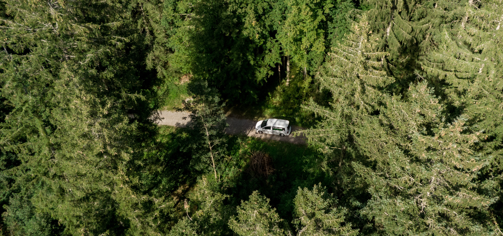 Drohnenaufnahme eines ABT E-Caddy auf einem Feldweg im Wald